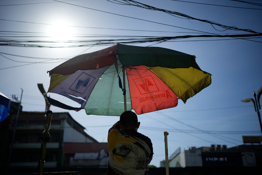 A vendor prepares his umbrella as hot days continue in Manila, Philippines on Monday, April 29, 2024. (AP Photo/Aaron Favila)