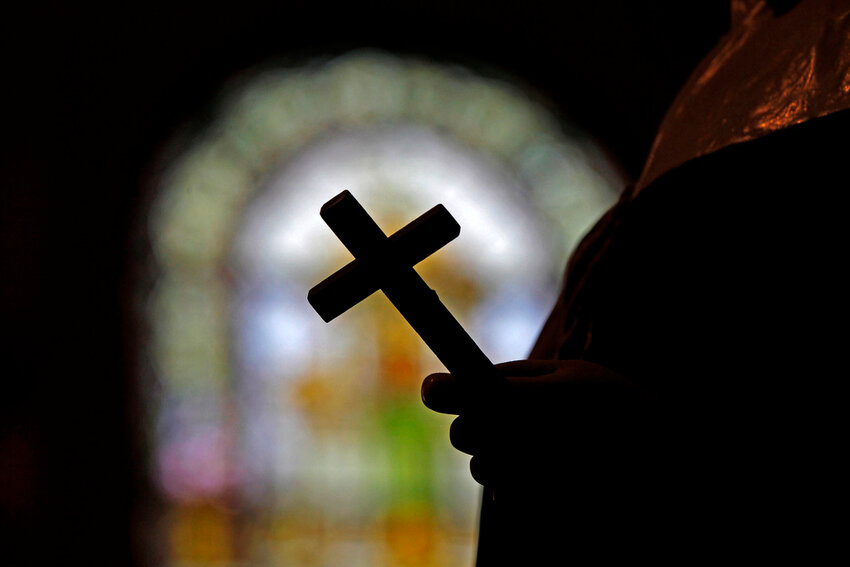 A man holds a cross inside a church in New Orleans. (AP Photo/Gerald Herbert, File)