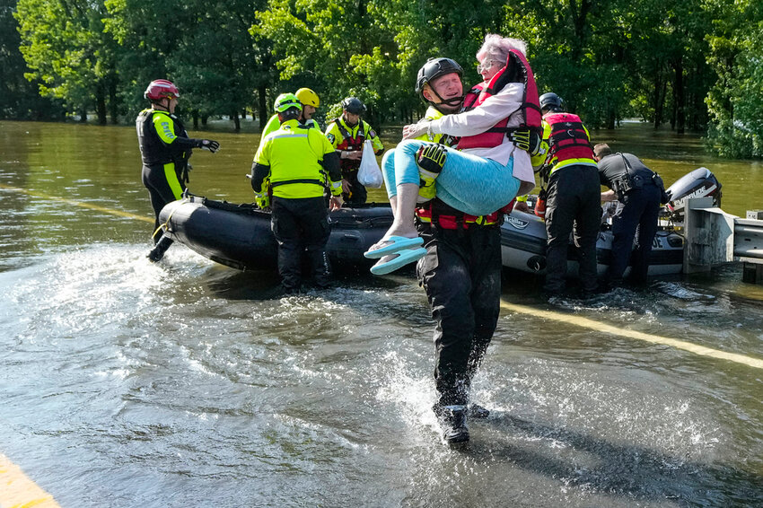 Conroe firefighter Cody Leroy carries a resident evacuated from her flooded home in a boat in the aftermath of a severe storm, Thursday, May 2, 2024, in Conroe, Texas. (Brett Coomer/Houston Chronicle via AP)