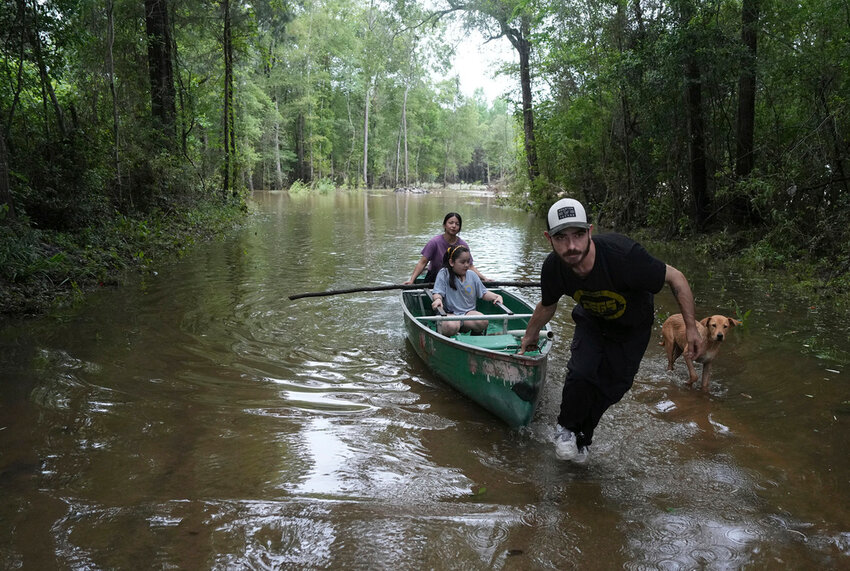 Alvaro Trevino pulls a canoe with Jennifer Tellez and Ailyn, 8, after they checked on their home on Sunday, May 5, 2024, in Spendora, Texas. (Elizabeth Conley/Houston Chronicle via AP)