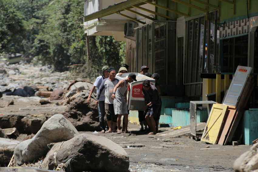 People carry a refrigerator at a village affected by a flash flood in Tanah Datar, West Sumatra, Indonesia, Sunday, May 12, 2024. Heavy rains and torrents of cold lava and mud flowing down a volcano's slopes on Indonesia's Sumatra island triggered flash floods that killed and injured a number of people, officials said Sunday. (AP Photo/Fachri Hamzah)