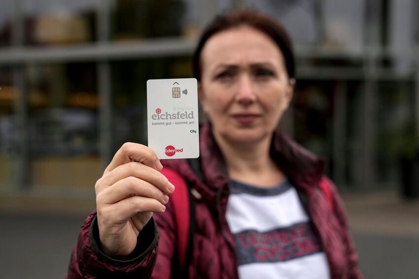 Erdina Laca, a 45-year-old asylum seeker, shows her special payment card in front of a grocery store, in Eichsfeld, Germany, Wednesday, April 24, 2024. (AP Photo/Ebrahim Noroozi)