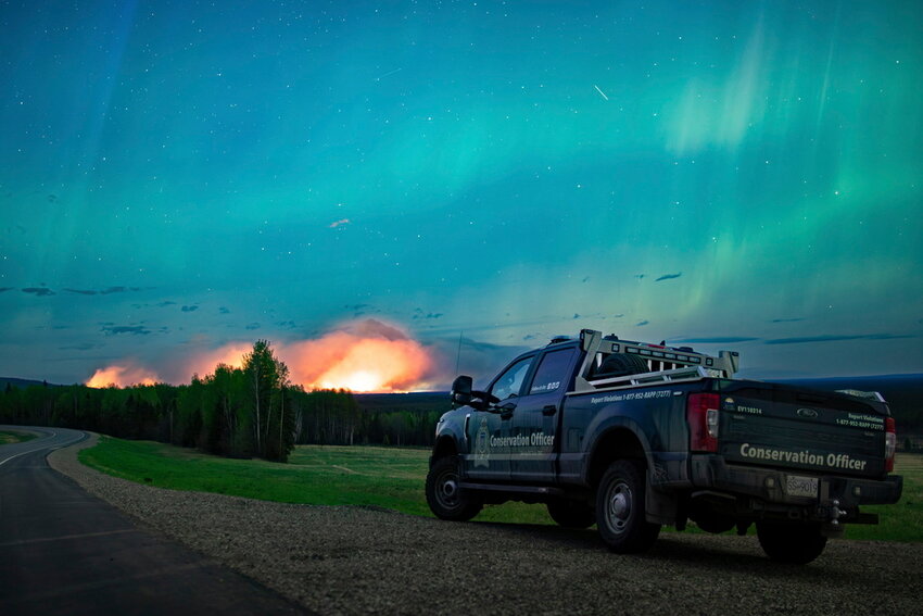 A wildfire burns, with the Aurora Borealis overhead, near Fort Nelson, British Columbia, Saturday, May 11, 2024. (Ministry of Water, Land and Resource Stewardship/The Canadian Press via AP)