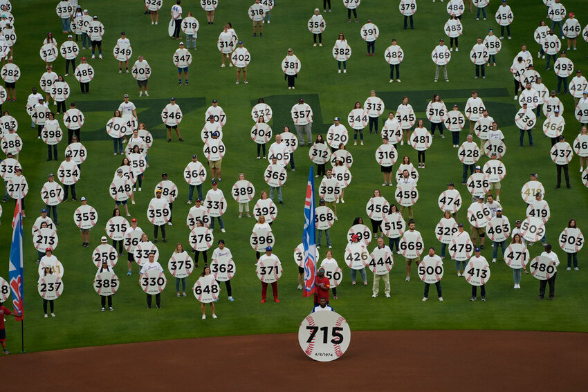 In honor of the 50th anniversary of Hank Aaron breaking Babe Ruth's home run record 715 fans match onto the field to each holding a sign to commemorate an Aaron home run before a game between New York Mets and Atlanta Braves Monday, April 8, 2024, in Atlanta. Aaron passed Ruth on April 8, 1974. (AP Photo/John Bazemore)