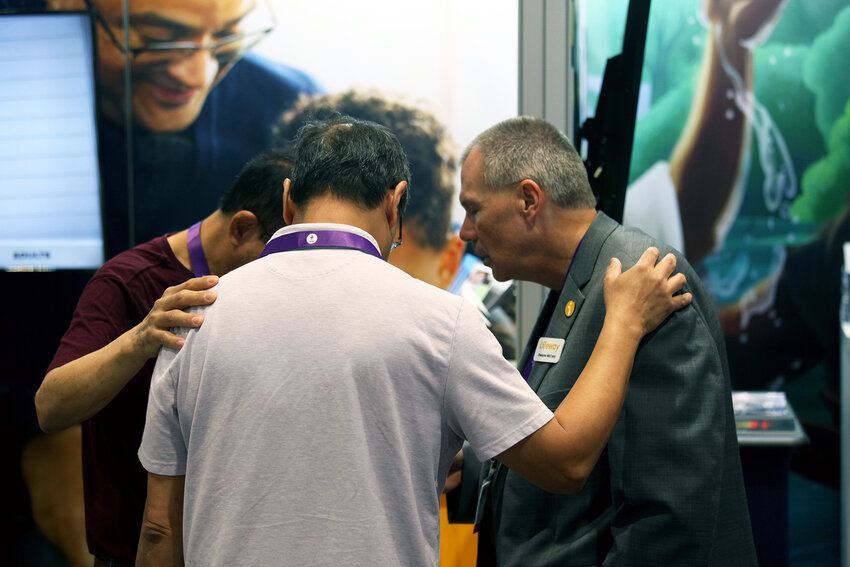 Lifeway employee Dwayne McCrary, right, prays with two attendees during the 2023 Southern Baptist Convention. (Photo/Lifeway)