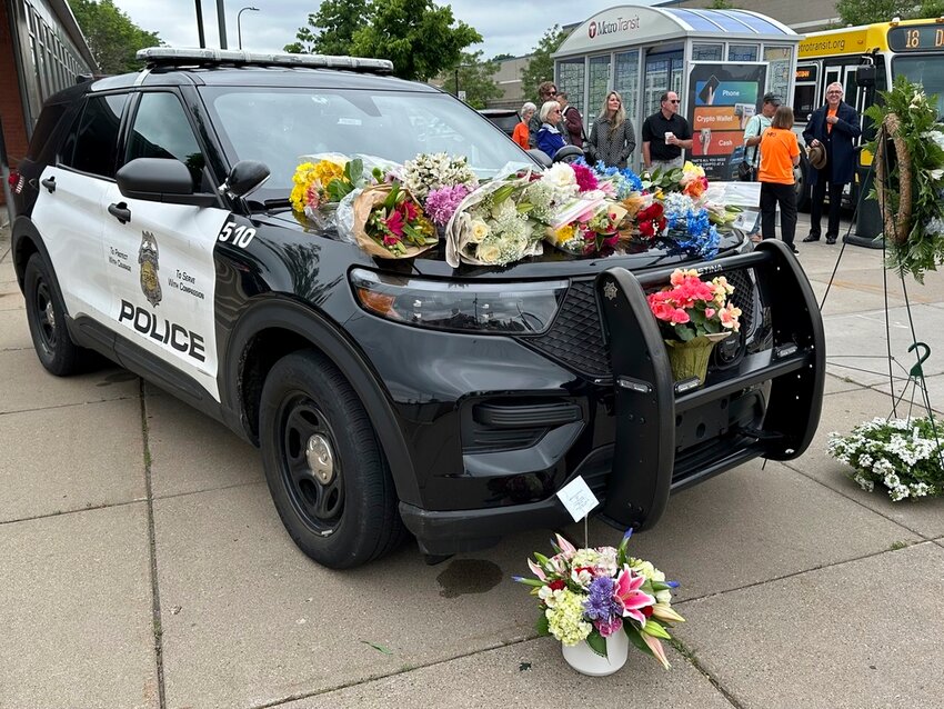 Mourners leave flowers on a police car at a precinct Friday, May 31, 2024, a day after an officer and two others were killed in a shooting. (AP Photo/Mark Vancleave)