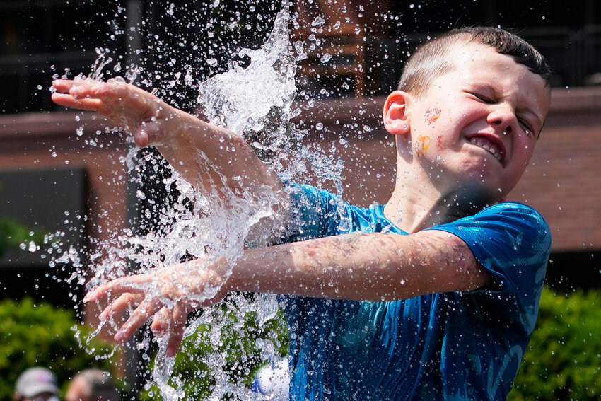 A boy cools off at a fountain outside Wrigley Field before a baseball game between the Chicago Cubs and St. Louis Cardinals as hot weather descends upon the Chicago area Sunday, June 16, 2024. (AP Photo/Nam Y. Huh