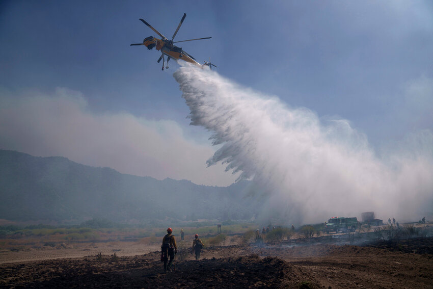 A helicopter drops water as crews fight the Post Fire, Sunday, June 16, 2024, in Lebec, Calif. (AP Photo/Eric Thayer)