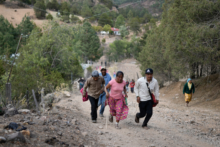 Rarámuri runner Teresa Sánchez is accompanied by residents as she competes in the Arihueta race in Cuiteco, Mexico, Saturday, May 11, 2024. (AP Photo/Eduardo Verdugo)