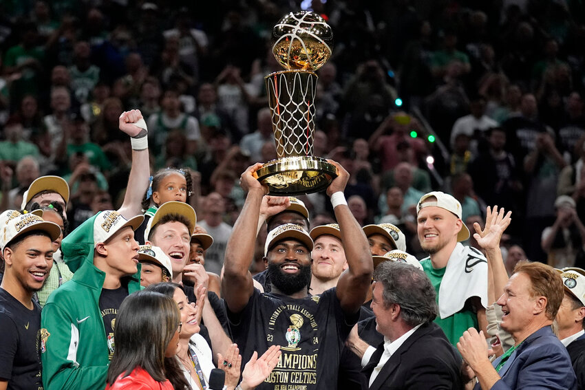 Boston Celtics guard Jaylen Brown, center, holds up the Larry O'Brien Championship Trophy as he celebrates with the team after they won the NBA championship over the Dallas Mavericks, Monday, June 17, 2024, in Boston. (AP Photo/Charles Krupa)