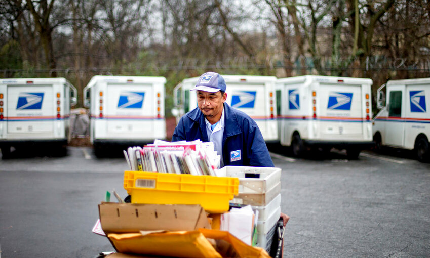 A U.S. Postal Service letter carrier gathers mail to load into his truck before making his delivery run in the East Atlanta neighborhood in Atlanta. (AP Photo/David Goldman, File)