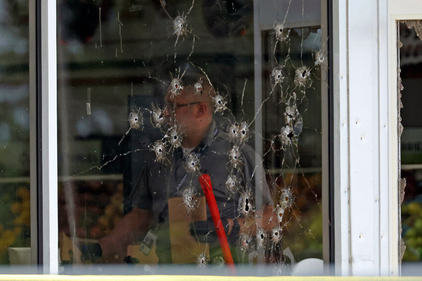 Damage can be seen to a front window as law enforcement officers work the scene of a shooting at the Mad Butcher grocery store in Fordyce, Ark., Friday, June 21, 2024. (Colin Murphey/Arkansas Democrat-Gazette via AP)
