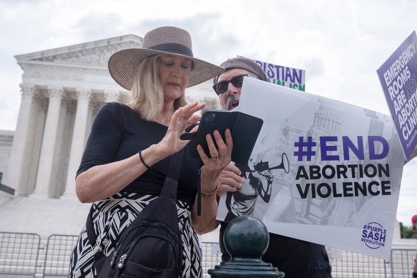 Katie Mahoney, left, and Rev. Patrick Mahoney, chief strategy officer for Stanton Healthcare, an Idaho-based pregnancy center that does not provide abortions, read the text of a Supreme Court decision outside the Supreme Court on Thursday, June 27, 2024, in Washington. (AP Photo/Mark Schiefelbein)