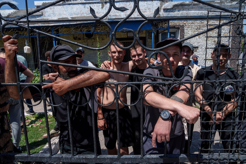 Prisoners stand behind the fence in a prison in the Dnipropetrovsk region, Ukraine, Friday, June 21, 2024. (AP Photo/Evgeniy Maloletka)