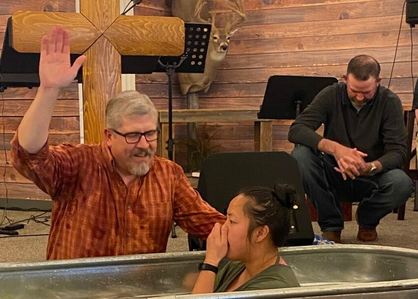 Scott Plath, pastor of South Fork Outdoorsmen Church in Rigby, Idaho, baptizes Mai Guimont while Deacon Brian Durkin prays. (Photo/Baptist Press)