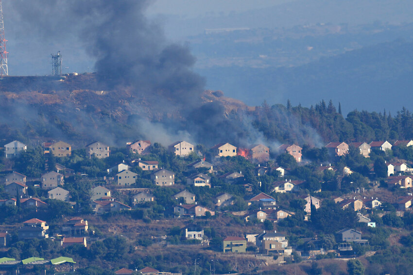 Fires and black smoke rise from between the houses of the northern Israeli border town of Metula, which was hit by Hezbollah shelling, as seen from the Lebanese side of the Lebanese town of Marjayoun, Lebanon, June 22, 2024. (AP Photo/File)
