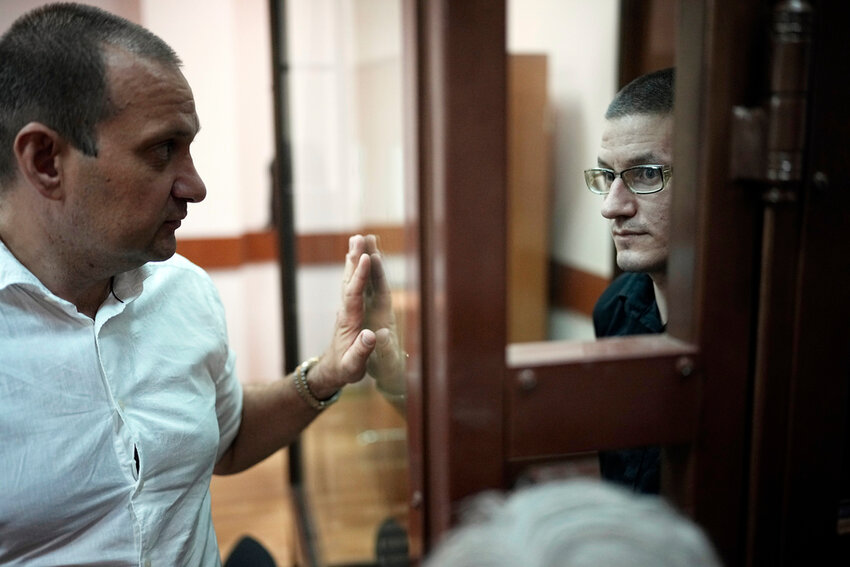 Robert Woodland, right, a Russia-born U.S. citizen, stands in a glass cage as he talks with his lawyer Stanislav Kshevitsky prior to a court hearing, Thursday, July 4, 2024, in Moscow, Russia. (AP Photo/Alexander Zemlianichenko)