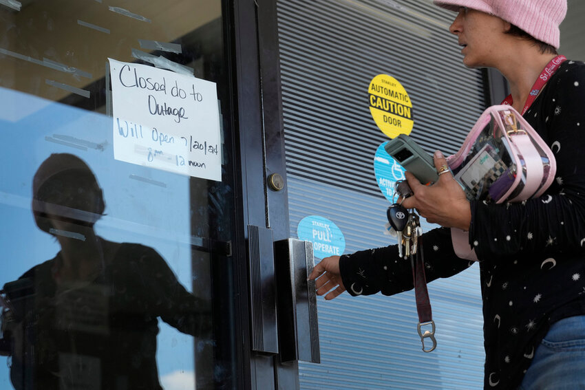 Danielle Tuttle tries the door to a department of motor vehicles location to find it locked and the location closed due to an outage Friday, July 19, 2024, in St. Louis. (AP Photo/Jeff Roberson)