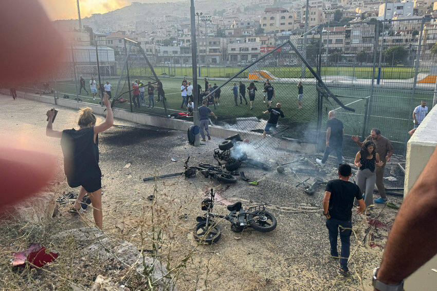 Residents rush to help injured children moments after a rocket attack hit a soccer field in the Druze town of Majdal Shams in the Golan Heights, Saturday, July 27, 2024. (AP Photo/Hassan Shams)