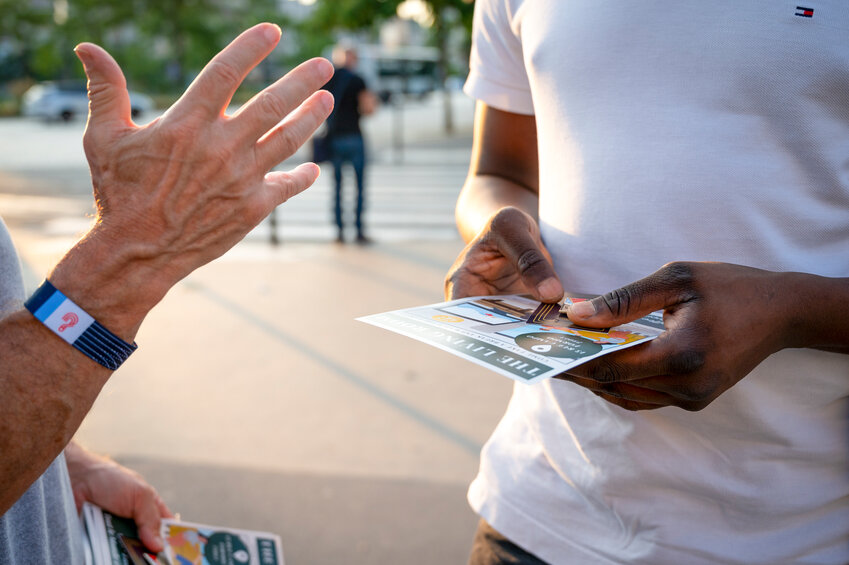 Gary Morris, from the First Baptist Church of Boaz in Boaz, Alabama, shares a gospel message using a Christian Olympic pin with a man on the streets of Paris. (Photo/IMB)