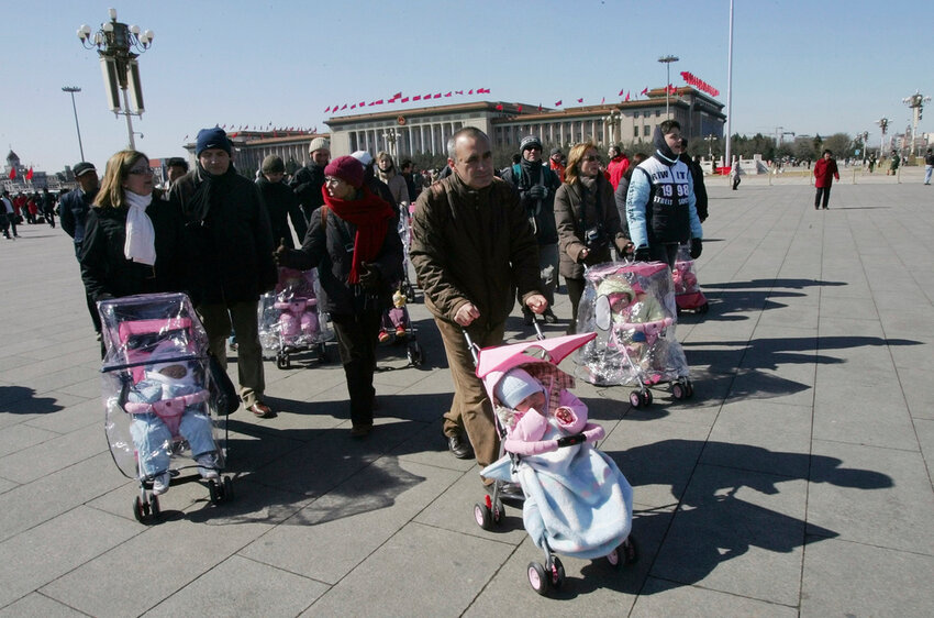 Spanish couples take their newly adopted Chinese children for a walk in Beijing's Tiananmen Square, March 7, 2007. (AP Photo/Greg Baker, File)