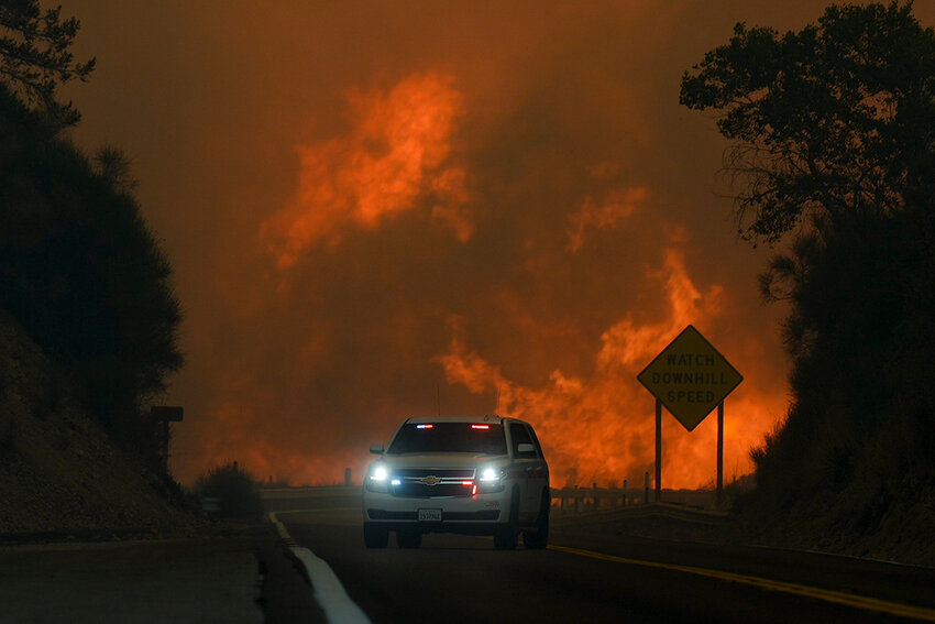 The Line Fire jumps highway 330 as an emergency vehicle is driven past Saturday, Sept. 7, 2024, near Running Springs, Calif. (AP Photo/Eric Thayer)