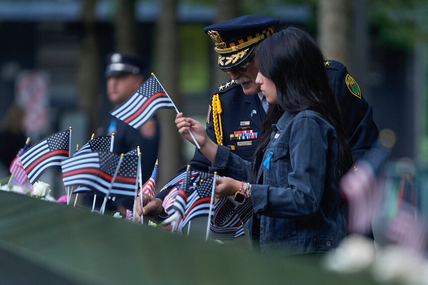 Sam Pulia, left, Willow Springs, Ill., police chief, places flags on the bronze parapets at the 9/11 Memorial on the 23rd anniversary of the Sept. 11, 2001 terror attacks Wednesday, Sept. 11, 2024, in New York. (AP Photo/Pamela Smith)