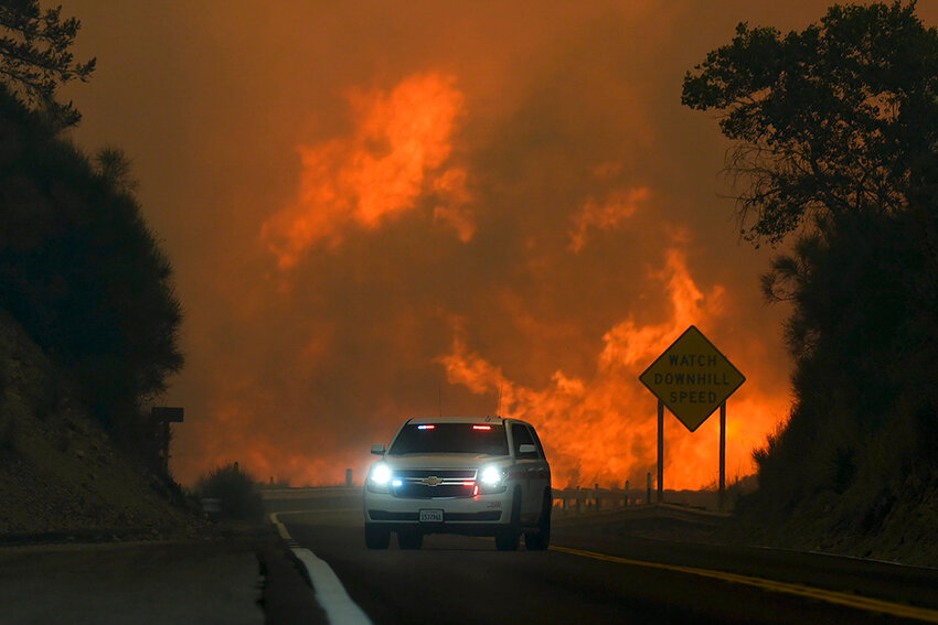 FILE - The Line Fire jumps Highway 330 as an emergency vehicle is driven past Saturday, Sept. 7, 2024, near Running Springs, Calif. (AP Photo/Eric Thayer, File)