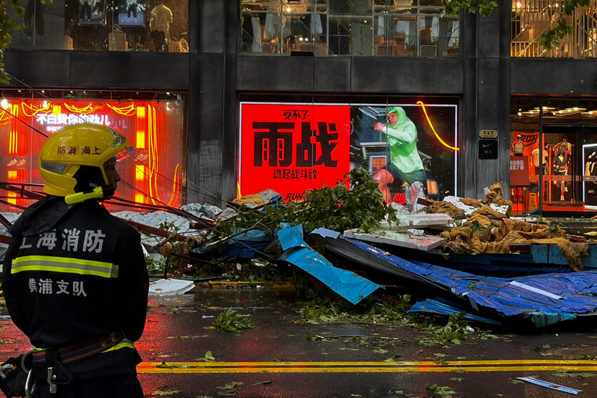 A firefighter stands near debris along a business street in the aftermath of Typhoon Bebinca in Shanghai, China, Monday, Sept. 16, 2024. (Chinatopix Via AP)