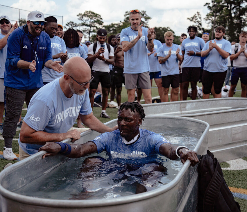 Jason Crumly from West Rome Baptist church baptizes Shorter University defensive back Deidric Gibson as head coach Zach Morrison, left, celebrates. (Photo/courtesy Zach Morrison)