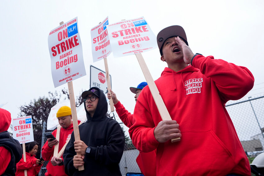 Boeing wing mechanic lead Lee Lara, who has worked for the company for 16 years, yells in response to honks from passing drivers as workers wave picket signs while striking Sunday, Sept. 15, 2024, near the company's factory in Everett, Wash. (AP Photo/Lindsey Wasson)