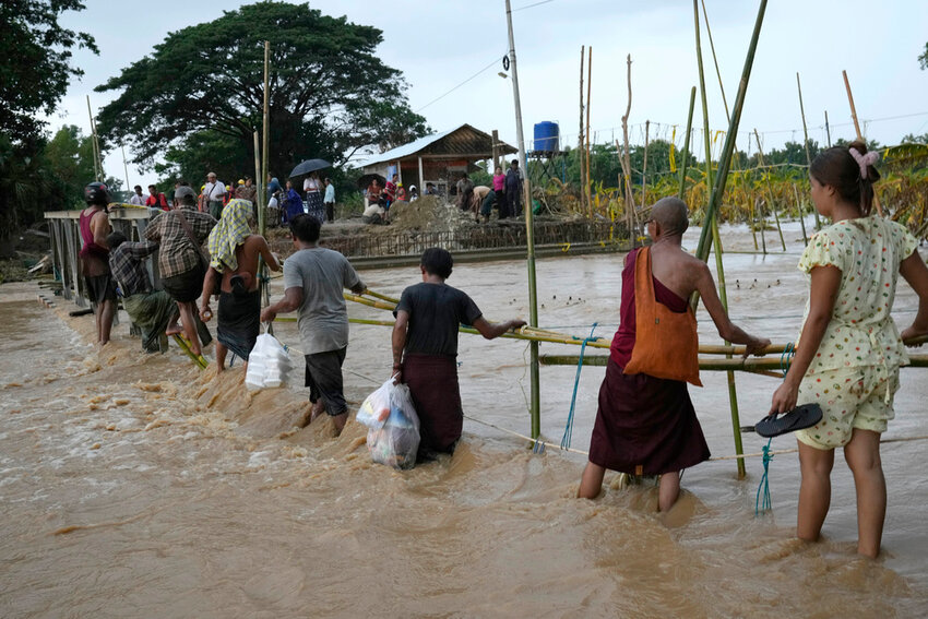 Local residents wade through flooded water at a broken bridge, in Naypyitaw, Myanmar, Tuesday, Sept. 17, 2024. (AP Photo/Aung Shine Oo)