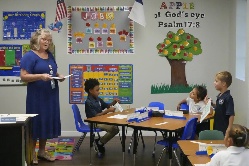 Kindergarten teacher Terrie Osborne helps students in her class at the Winter Garden Christian Academy,, Aug. 29, 2024, in Winter Garden, Fla. (AP Photo/John Raoux)