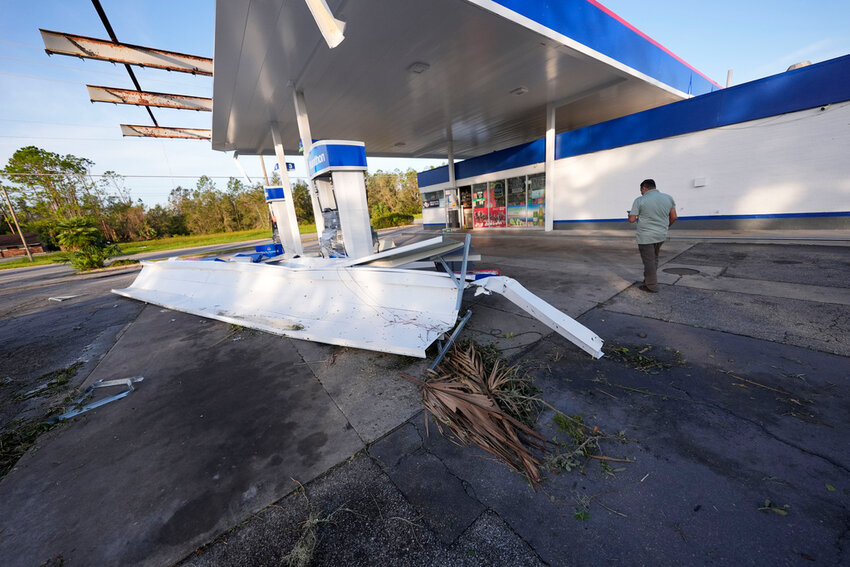 Faisal Bakkal, an employee of a Marathon gas station, walks away from damage in the aftermath of Hurricane Helene, in Perry, Fla., Friday, Sept. 27, 2024. (AP Photo/Gerald Herbert)