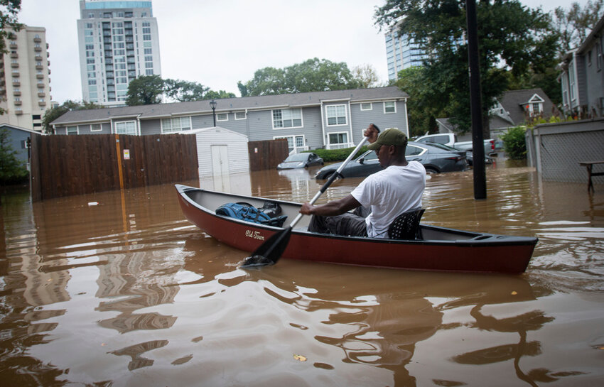 A man paddles a canoe to rescue residents and their belongings at a flooded apartment complex after Hurricane Helene passed the area on Friday, Sept. 27, 2024, in Atlanta. (AP Photo/Ron Harris)