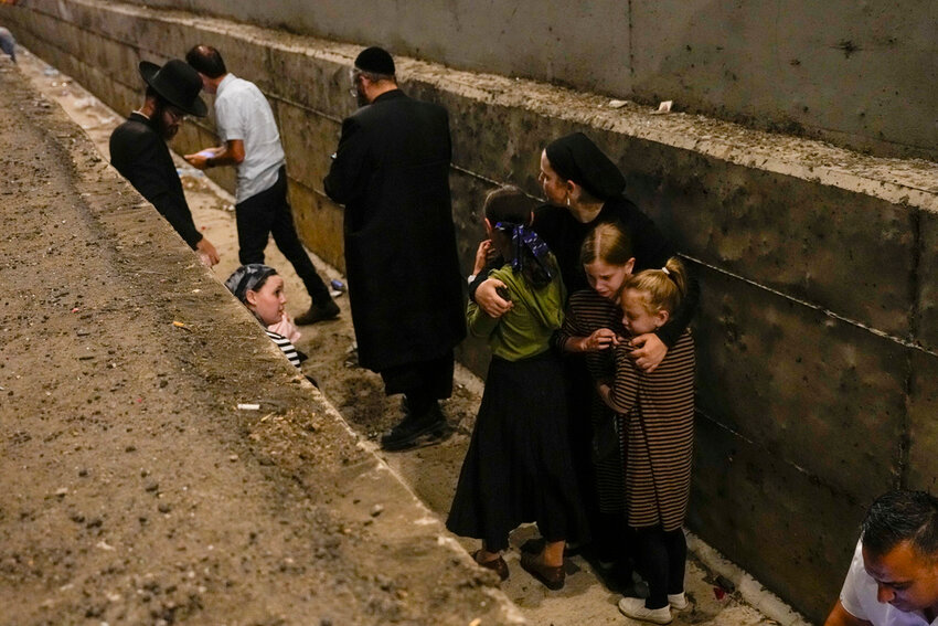 People take cover on the side of the road as a siren sounds a warning of incoming missiles fired from Iran on a freeway in Shoresh, between Jerusalem and Tel Aviv in Israel Tuesday, Oct. 1, 2024.(AP Photo/Ohad Zwigenberg)