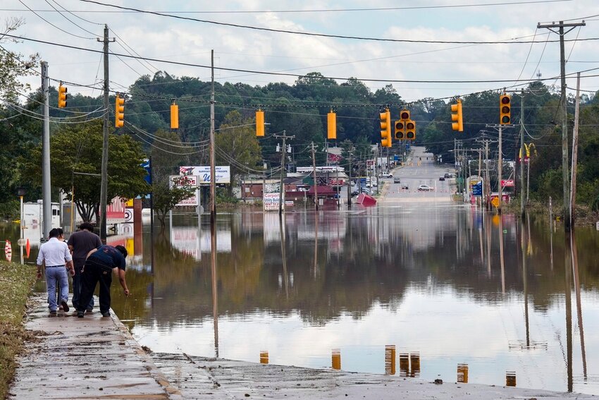 A passerby checks the water depth of a flooded road, Saturday, Sept. 28, 2024, in Morganton, N.C. (AP Photo/Kathy Kmonicek)