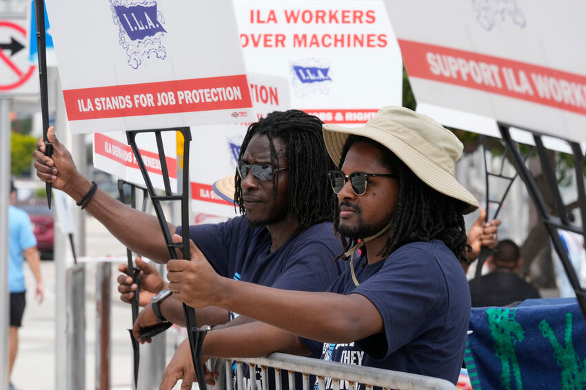 Dockworkers from Port Miami display signs at a picket line Thursday, Oct. 3, 2024, in Miami. (AP Photo/Marta Lavandier)