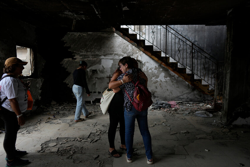 People hug at the house of Maayan and Yuval Bar, killed a year ago in a terror attack by Hamas, at the Kibbutz Be'eri, an Israeli communal farm on the Gaza border, on Monday, Oct. 7, 2024. (AP Photo/Ohad Zwigenberg)