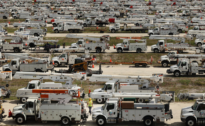 Duke Energy project manager Tiger Yates, bottom center, walks among the hundreds of lineman trucks staged Tuesday, Oct. 8, 2024. at The Villages, Fla. in preparation for Hurricane Milton. (Stephen M. Dowell/Orlando Sentinel via AP)