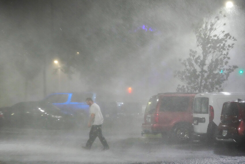 Max Watts, of Buford, Ga., walks in the parking lot to check on a trailer parked outside the hotel where he is riding out Hurricane Milton with coworkers, Wednesday, Oct. 9, 2024, in Tampa, Fla. Watts, who works for a towing company, was deployed with colleagues to Florida to aid in the aftermath of the storm. (AP Photo/Julio Cortez)