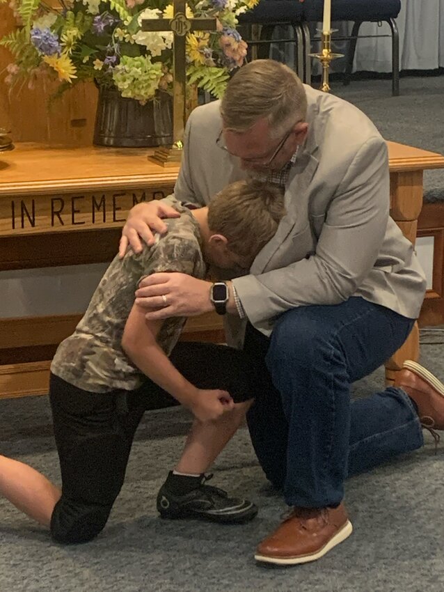 Pastor John Thompson prays with his son, Bryant, who made his public profession of faith during the church’s revival.