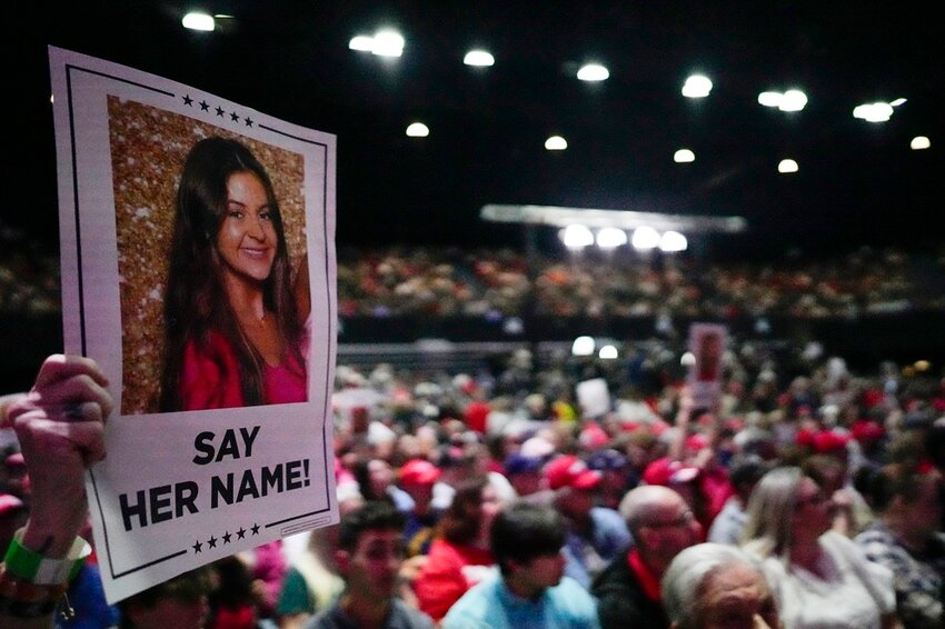 A supporter holds a sign with a photo of Laken Riley before Republican presidential candidate former President Donald Trump speaks at a campaign rally Saturday, March 9, 2024, in Rome, Ga. (AP Photo/Mike Stewart, File)