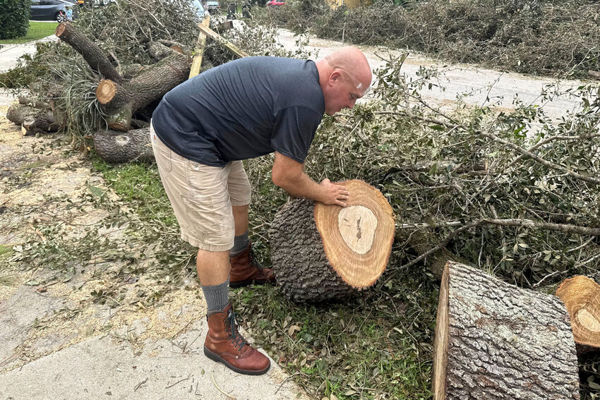 Tony Brazzale removes part of a tree felled by a tornado from in front of his house in Wellington, Fla., Friday, Oct. 11, 2024. (AP Photo/Stephany Matat)