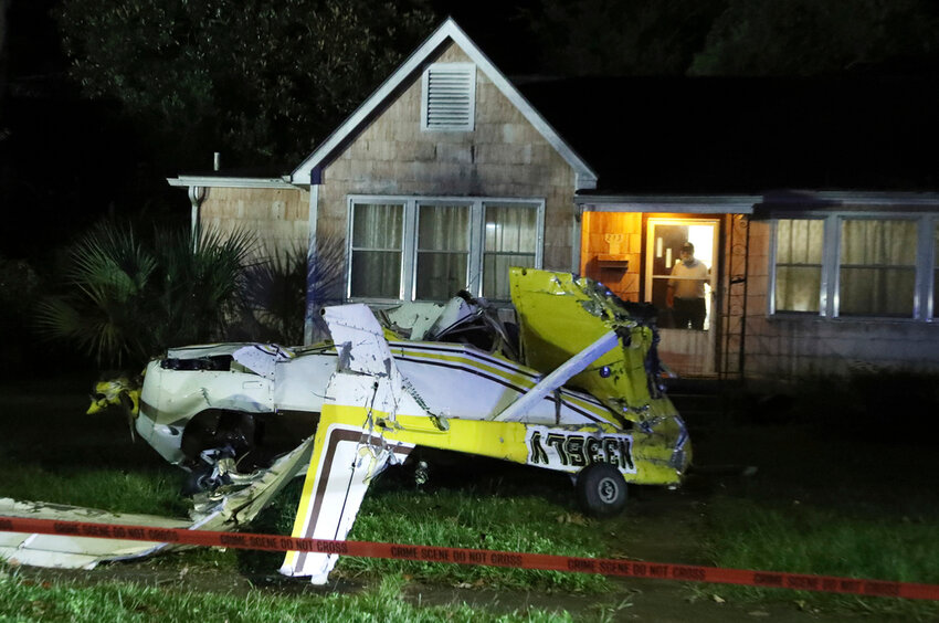 A man looks out the front door of his home after a Cessna crashed in the front yard in Savannah, Ga., Sunday, Oct. 13, 2024. (Richard Burkhart/Savannah Morning News via AP)