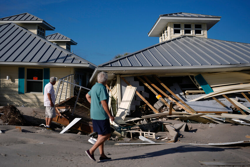 Property owners who preferred not to be named assess damage to their home and business, which bears orange notices calling for demolition, after the passage of Hurricane Milton, on Manasota Key in Englewood, Fla., Sunday, Oct. 13, 2024. (AP Photo/Rebecca Blackwell)