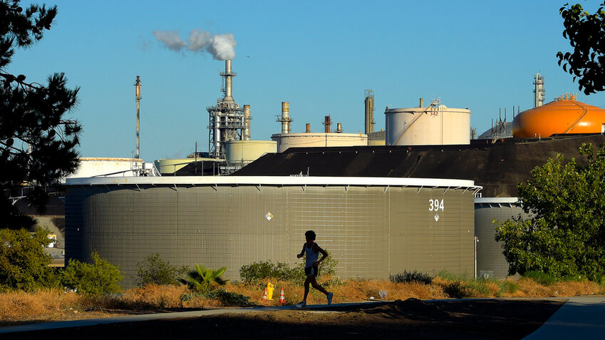 FILE - A jogger runs in front of the Phillips 66 refinery, July 16, 2014, in the Wilmington area of Los Angeles. (AP Photo/Mark J. Terrill, File)