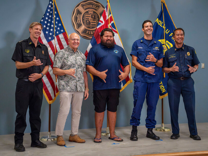 From left, Acting Director of Honolulu Ocean Safety Kurt Lager, Honolulu Mayor Rick Blangiardi, lifeguard Noland Keaulana, Coast Guard Lt. Cmdr. Nicholas Iannarone and Honolulu Deputy Fire Chief Jason Samala make shaka gestures as they stand for a photo at a news conference for a rescue of a 17-year-old kayaker in Honolulu on Thursday, Oct. 17, 2024. (Jennifer Nilson/U.S. Coast Guard via AP)