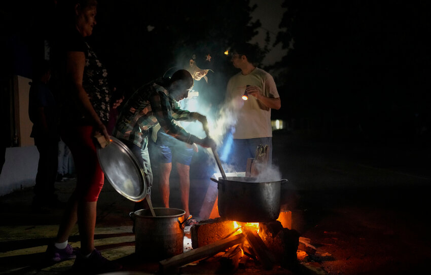 Residents prepare soup over an open fire during a blackout following the failure of a major power plant in Havana, Cuba, Saturday, Oct. 19, 2024. (AP Photo/Ramon Espinosa)