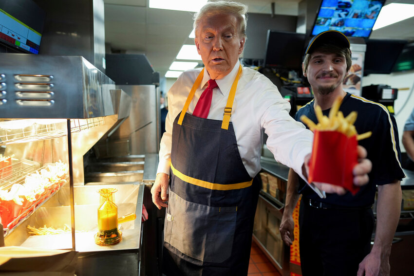 Republican presidential nominee former President Donald Trump, left, hands off an order of fries after working alongside an employee during a visit to McDonald's in Feasterville-Trevose, Pa., Sunday, Oct. 20, 2024. (Doug Mills/The New York Times via AP, Pool)